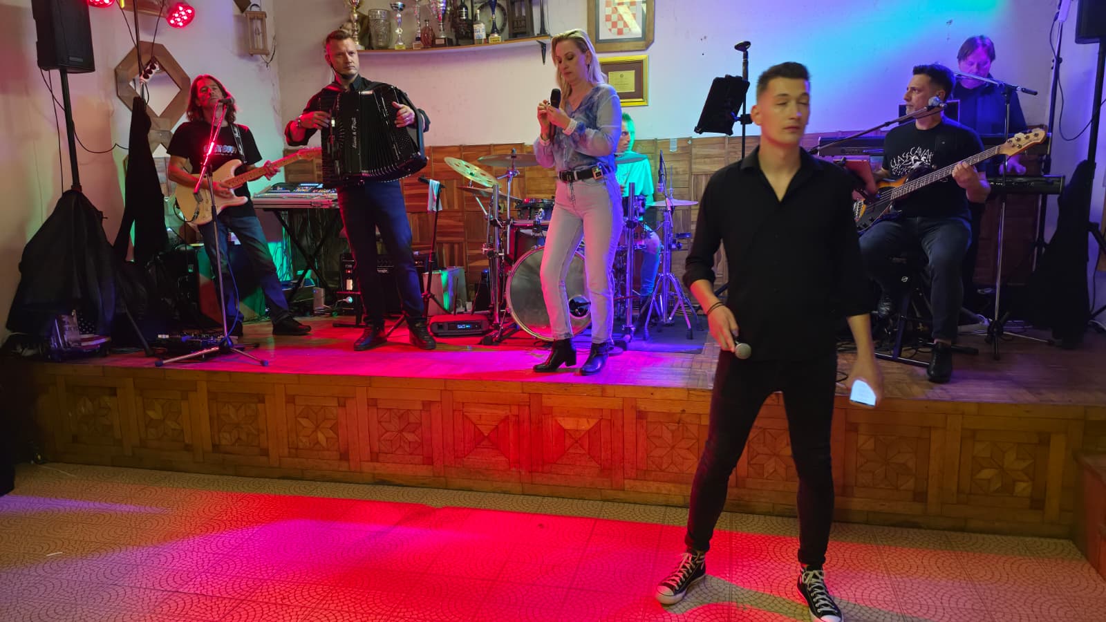 Joker Band u punom sastavu na pozornici vatrogasnog doma — pjevač, pjevačica, harmonika, gitare i bubnjevi
