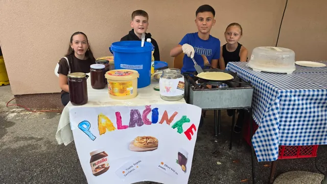 Mladi ponosno poziraju za štandom s palačinkama