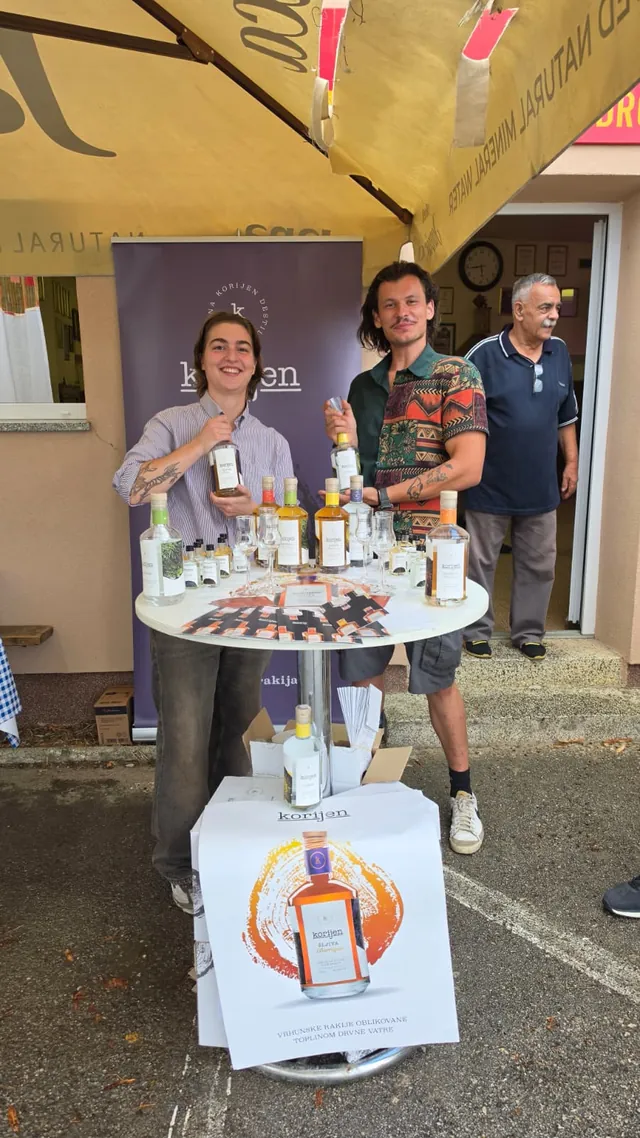 Osoblje destilerije Korijen pozira uz stol s bocama
