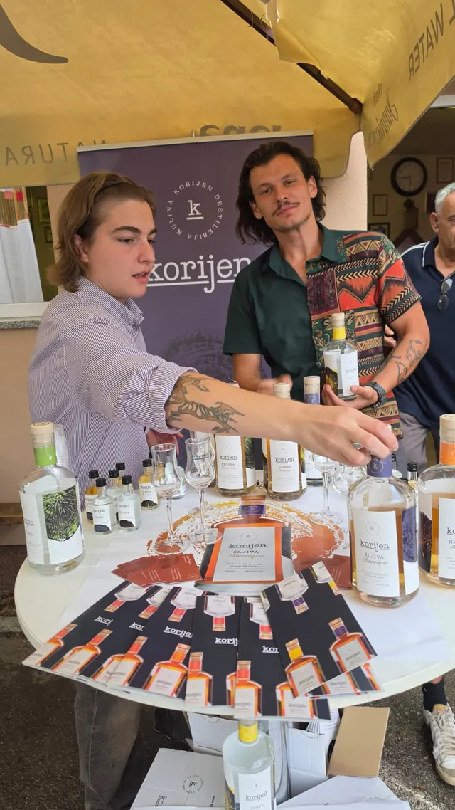 Posluživanje rakije s bocama i čašama na štandu Korijen