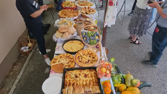 Košare kruha i peciva uz košaricu šljiva i grožđa