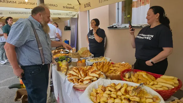 Domaćice u tamnim majicama nude pecivo posjetitelju