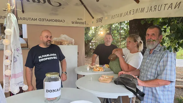 Gosti uz stolove i staklenku za donacije pod suncobranom
