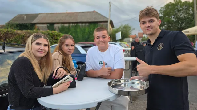 Mladi gosti za stolom vani uz člana ekipe s pladnjem