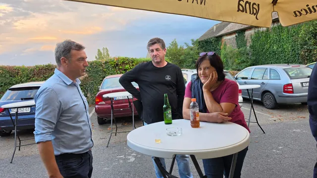 Gosti razgovaraju za stolom na parkiralištu pod suncobranom