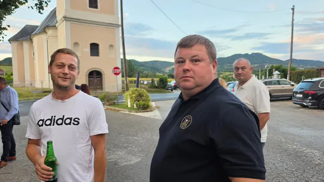 Dvojica gostiju razgovaraju vani uz crkvu