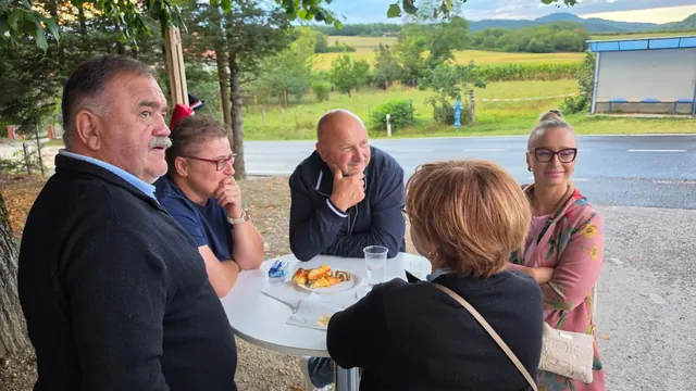 Društvo za visokim stolom uz kolače kraj ceste