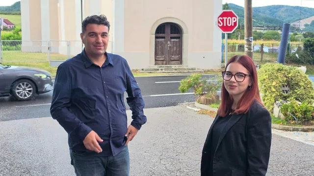 Dvoje gostiju pozira ispred kapele uz znak stop
