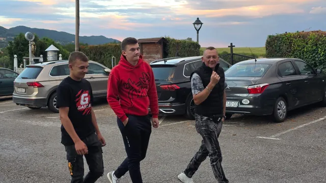 Dvojica mladića i gost dolaze parkiralištem u suton