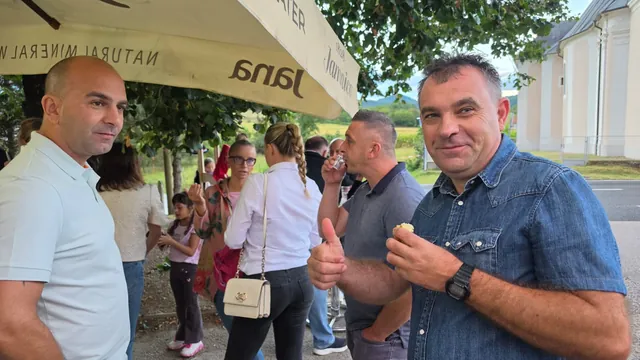 Gost s kolačem pokazuje palac gore pod suncobranom