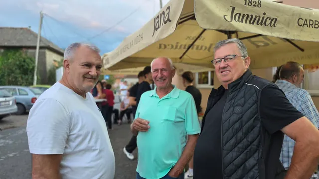 Trojica nasmijanih gostiju druže se pod suncobranima