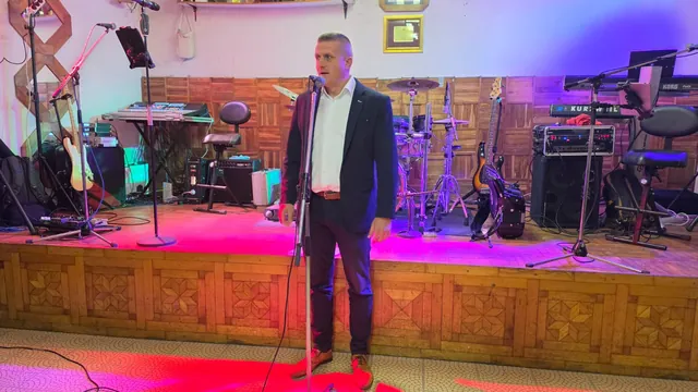 Govornik u odijelu obraća se publici ispred pozornice