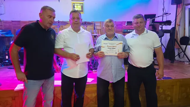 Dobitnik ponosno drži brončanu diplomu uz organizatore