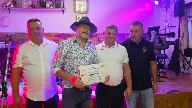 Dobitnik sa šeširom drži srebrnu diplomu uz organizatore