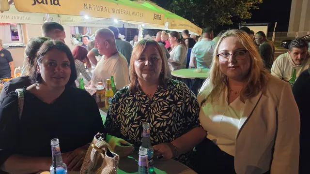 Tri posjetiteljice za stolom pod suncobranima u večernjim satima