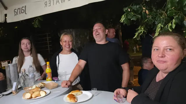 Gosti uz stajaći stol s pecivima pod suncobranom navečer