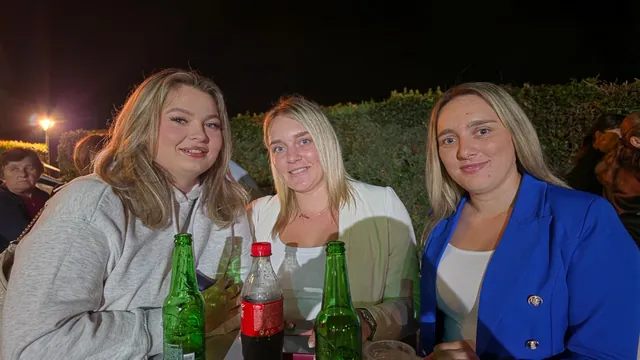 Tri mlade posjetiteljice za stolom u večernjoj atmosferi