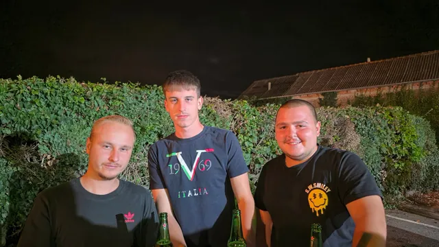 Trojica mladića s pićem poziraju u večernjim satima