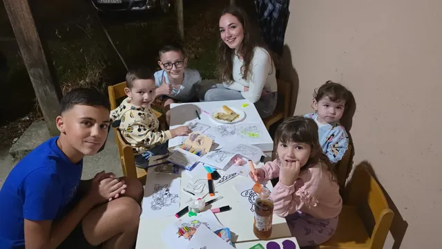 Djeca s bojicama i crtežima za stolom dječjeg kutka