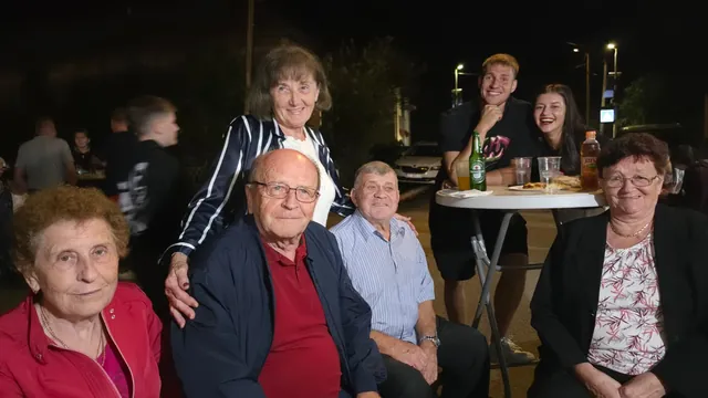 Više generacija okupljeno oko stajaćeg stola navečer