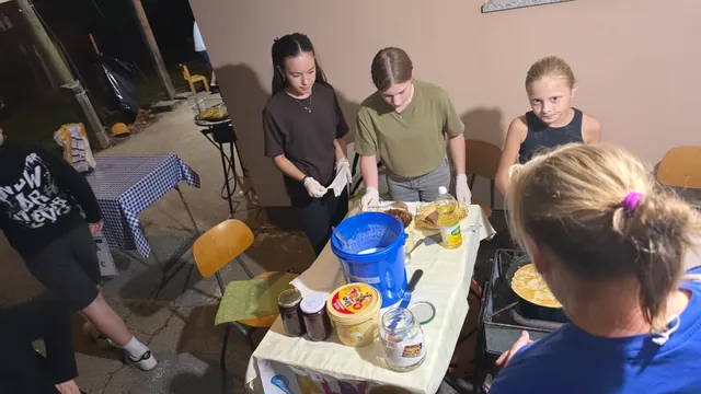 Mladež s rukavicama peče palačinke na štandu uz zid