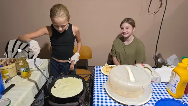 Djevojčica peče palačinku u tavi na plinskom kuhalu