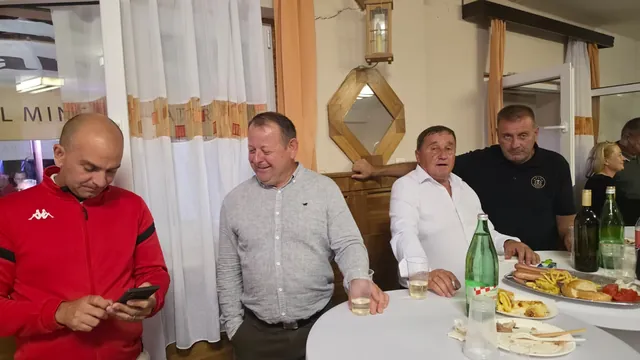 Muškarci razgovaraju uz stol s hranom i pićem
