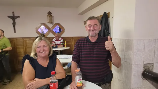 Nasmijani par pozira s podignutim palcem uz stol