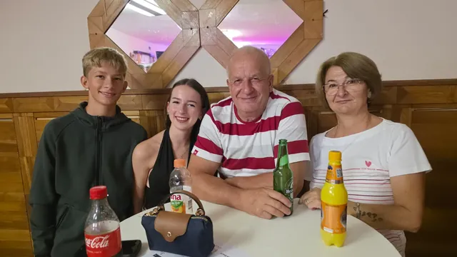Obitelj pozira za okruglim stolom s osvježavajućim pićima