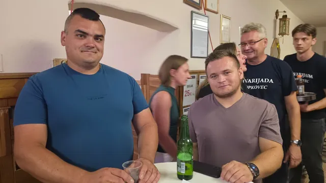 Dvojica muškaraca poziraju uz stol s pićem