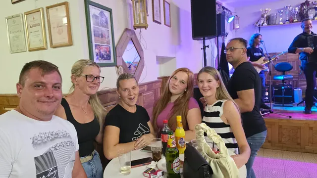 Društvo za stolom dok u pozadini svira sastav