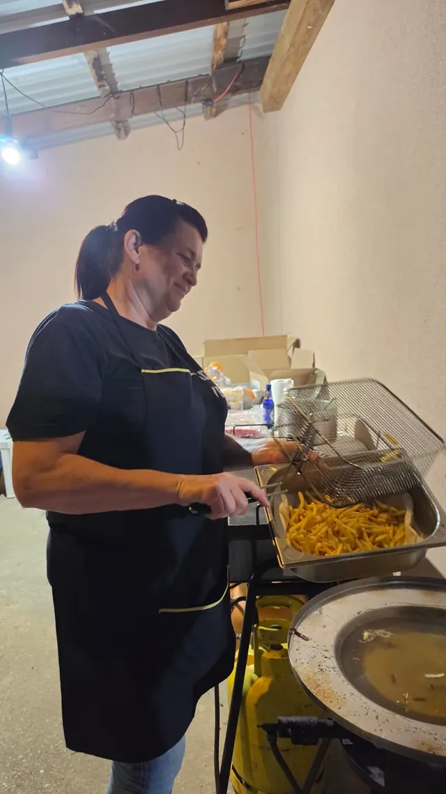 Članica ekipe prži pomfrit u fritezi ispred doma